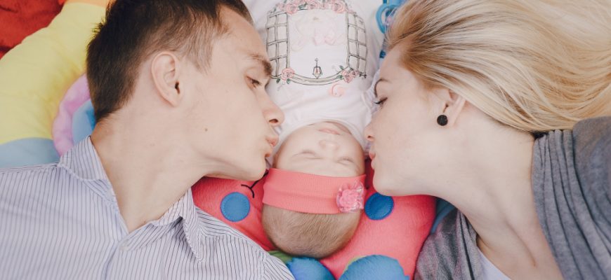 young parents kissing their baby